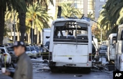A man walks past the bus that exploded Tuesday in Tunis, Nov.25, 2015. Tunisia's president declared a 30-day state of emergency across the country and imposed an overnight curfew for the capital after an explosion struck a bus.