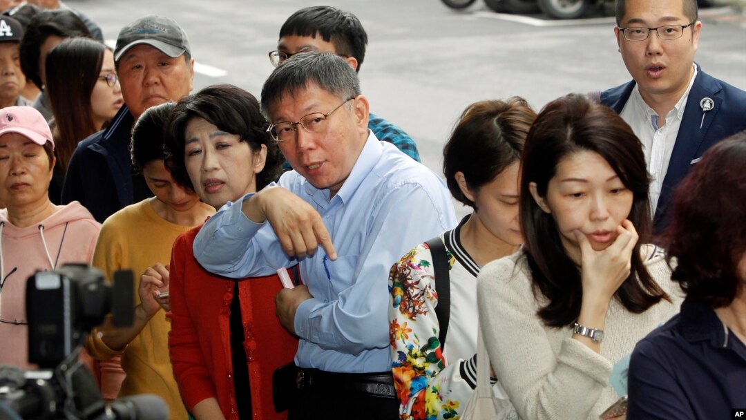Taipei Mayor and city mayoral candidate Ko Wen-je, center, lines up at a polling station, Nov. 24, 2018, in Taipei, Taiwan.