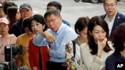 Taipei Mayor and city mayoral candidate Ko Wen-je, center, lines up at a polling station, Nov. 24, 2018, in Taipei, Taiwan.