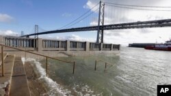 FILE - In this Jan. 11, 2017, photo, water from a king tide floods a staircase along the Embarcadero in San Francisco. California's Ocean Protection Council decided April 26, 2017, to update its sea-rise guidance for state and local governments.