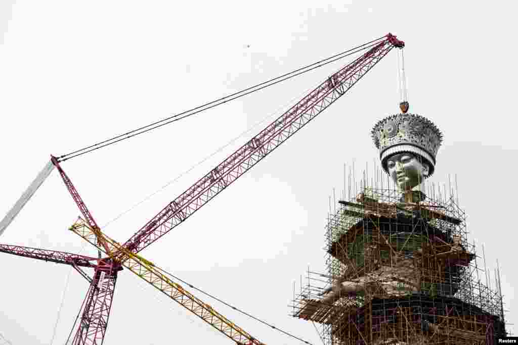 The head of a legendary ethnic Miao goddess statue is lifted into place at the construction site of the statue, in Jianhe County, Guizhou Province, China.