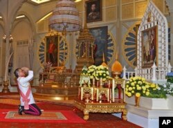 In this photo released by Bureau of the Royal Household, Thailand 's new king Maha Vajiralongkorn Bodindradebayavarangkun pays his respects to a portrait of the late Thai King Bhumibol Adulyadej and Thai Queen Sirikit at the Dusit Palace Dec.1, 2016.