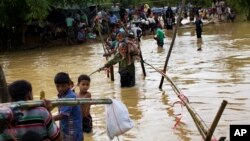 Rohingya Muslims cross a flooded area to find an alternate shelter after their camp was inundated with rainwater near Balukhali refugee camp, Bangladesh, Sept. 19, 2017. 