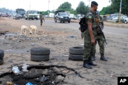 FILE - Police officers stand next to a checkpoint near the site of a blast in Kaduna, Nigeria, July 24, 2014.