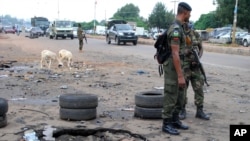 FILE - Police officers stand next to a checkpoint near the site of a blast in Kaduna, Nigeria, July 24, 2014.