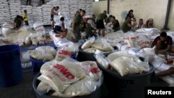 Members of the Armed Forces of the Philippines help out volunteers repacking food rations for victims of Typhoon Noul at the Department of Social Welfare Development (DSWD) headquarters in Pasay city, south of Manila, May 9, 2015.