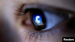 FILE - A picture illustration shows a Facebook logo reflected in a person's eye.