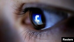 FILE - A picture illustration shows a Facebook logo reflected in a person's eye.