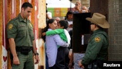 U.S. Border patrol agents stand at an open gate along the Mexico border to allow Luis Eduardo Hernandez-Bautista hug Ty'Jahnae Williams and his father Eduardo Hernandez (not in view), as part of Universal Children's Day at the Border Field State Park, California, Nov. 19, 2016. 