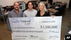 The Skysource/Skywater Alliance co-founders David Hertz, left, his wife Laura Doss-Hertz, right, and project designer Willem Swart pose for a photo with an image of their $1.5 million prize Wednesday, Oct. 24, 2018, in Los Angeles. (AP Photo/Marcio Jose S