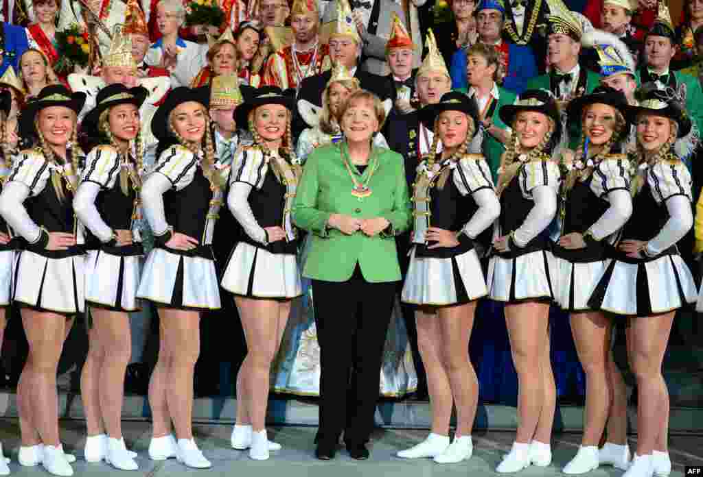 Kanselir Jerman Angela Merkel (tengah) berpose bersama kelompok penari yang akan berpartisipasi dalam festival karnaval di Berlin.