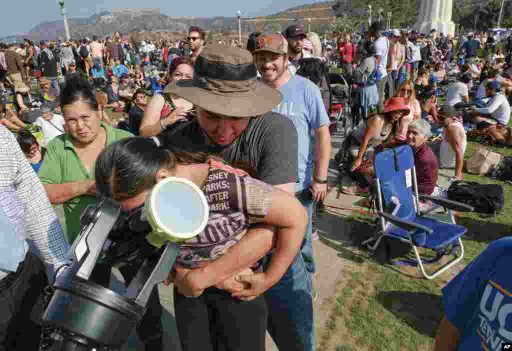 Kayley Terrez is lifted up to see the solar eclipse through a telescope as a large crowd gathers at the Griffith Observatory to watch the solar eclipse in Los Angeles Monday, Aug. 21, 2017. (AP Photo/Richard Vogel)