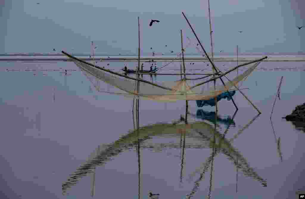 Para nelayan duduk di perahu mereka untuk menangkap ikan di sungai Brahmaputra di Guwahati, India (Foto: AP).