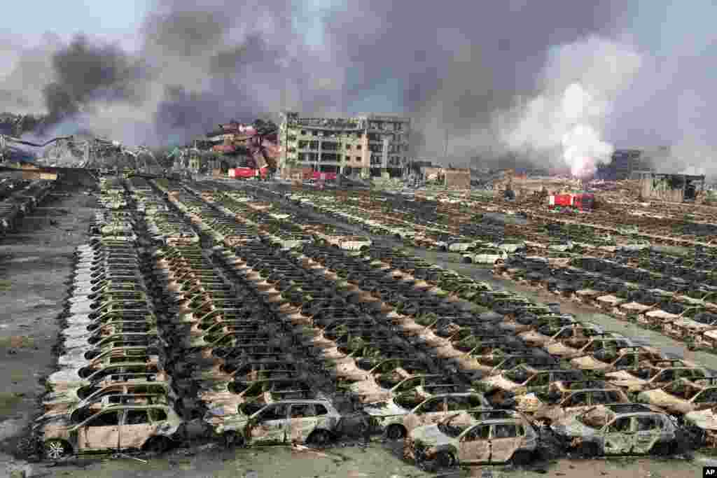 Smoke billows out from the site of an explosion that reduced a parking lot filled with new cars to charred remains at a warehouse in northeastern China's Tianjin municipality. Huge explosions in the warehouse district sent up massive fireballs that turned the night sky into day in the port city, officials and witnesses said.