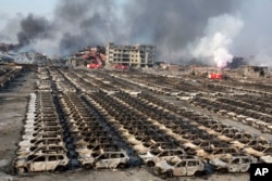 Smoke billows out from the site of an explosion that reduced a parking lot filled with new cars to charred remains at a warehouse in northeastern China's Tianjin municipality, Aug. 13, 2015.