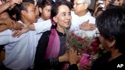 ရန်ကုန်အပြည်ပြည်ဆိုင်ရာလေဆိပ်ကို ပြန်ရောက်လာတဲ့ ဒေါ်အောင်ဆန်းစုကြည်နဲ့ ကြိုဆိုနှုတ်ဆက်သူများကိုတွေ့ရစဉ်။ (ဇွန် ၁၄၊ ၂၀၁၅)