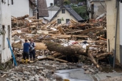 Two men remove debris of houses destroyed by the floods in Schuld near Bad Neuenahr, western Germany. Heavy flooding turned streams and streets into raging torrents, sweeping away cars and causing some buildings to collapse.