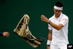 Kei Nishikori melempar handuknya dalam laga tunggal putera melawan petenis Italia,Marco Cecchinato, pada pembukaan turnamen Wimbledon di London, 3 Juli 2017.