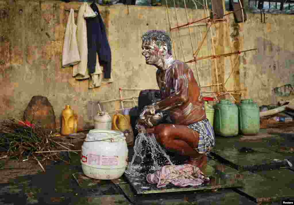 인도 뉴델리 거리에서 한 남성이 목욕을 하고 있다.