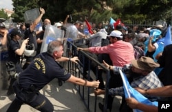 防暴警察用胡椒喷剂阻止维吾尔抗议者冲破中国驻安卡拉大使馆外的保护障碍。（2015年6月9日）