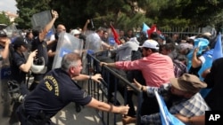 FILE - Riot police use pepper spray to push back a group of Uighur protesters who try to break through a barricade outside the Chinese Embassy in Ankara, Turkey, June 9. 2015.