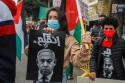 Warga Arab Israel mengangkat plakat bergambar PM Israel Benjamin Netanyahu yang bertuliskan "Tersesat" dalam bahasa Arab, dalam aksi unjuk rasa saat dia mengunjungi Nazareth, kota Arab terbesar di Israel,13 Januari 2021.