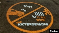 A warning sign is projected next to a zebra crossing in Ilsan, South Korea, March 12, 2019.