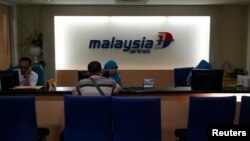 A Malaysia Airlines representative serves a customer at its ticket office in Jakarta July 18, 2014. 