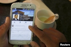 FILE - A person uses a smartphone to look at the Facebook page of Cambodia's Prime Minister Hun Sen during breakfast at a restaurant in central Phnom Penh, Cambodia, Oct. 7, 2015.