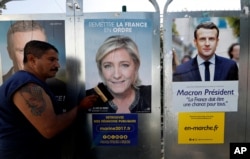 FILE - Campaign posters of French National Front (FN) political party leader Marine Le Pen, center, and head of the political movement En Marche! (Onwards!) Emmanuel Macron, right, are seen in Antibes, France, April 14, 2017.