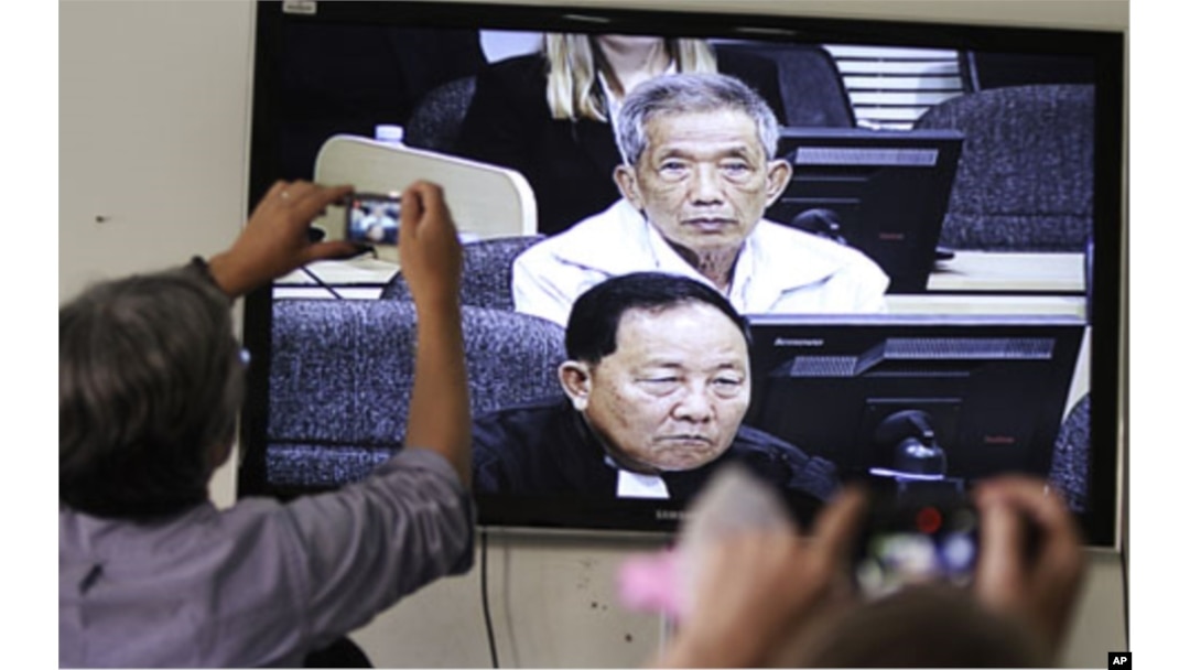 FILE - Journalists take photographs of a television screen showing the trial of Duch, former chief of the S-21 prison, at the Extraordinary Chambers in the Courts of Cambodia (ECCC) on the outskirts of Phnom Penh, Feb. 3, 2012.