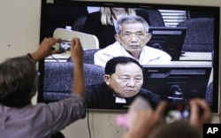 FILE - Journalists take photographs of a television screen showing the trial of Duch, former chief of the S-21 prison, at the Extraordinary Chambers in the Courts of Cambodia (ECCC) on the outskirts of Phnom Penh, Feb. 3, 2012.
