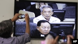 Journalists take photographs at a television screen showing the trial of Kaing Guek Eav alias Duch, former chief of the S-21 prison, at the Extraordinary Chambers in the Courts of Cambodia (ECCC) on the outskirts of Phnom Penh, February 3, 2012. 