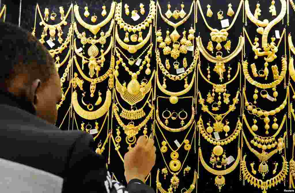 A man arranges gold jewels on a display inside a jewelry shop at Wuse market in Abuja, Nigeria.
