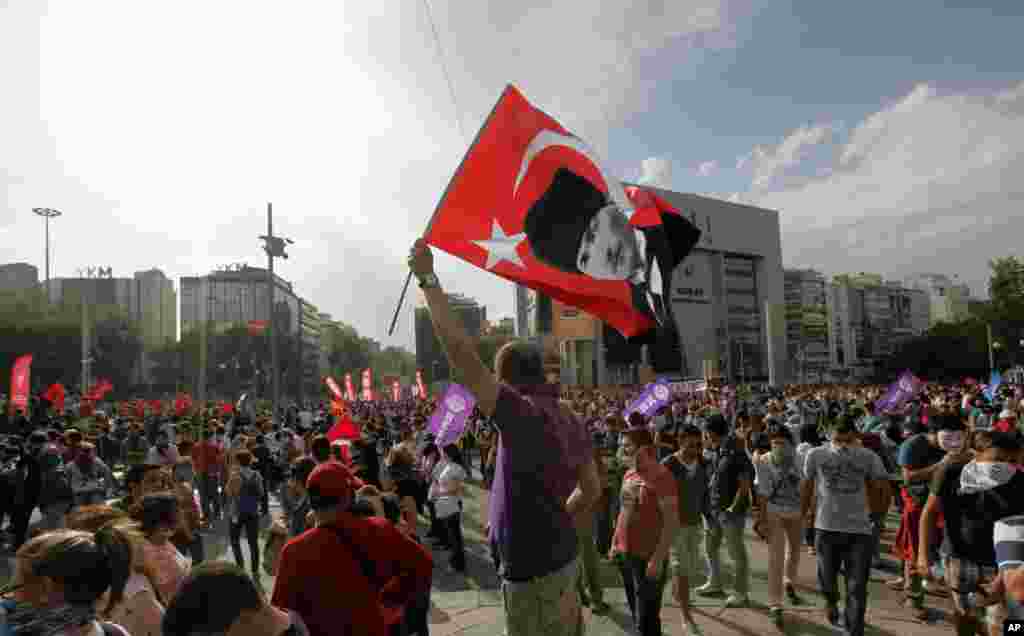 Seorang pria melambaikan bendera dengan gambar pendiri Turki Kemal Ataturk saat ribuan pemuda Turki berkumpul di Alun-Alun Kizilay, Ankara (2/6). (AP/Burhan Ozbilici)