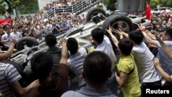 Protesters overturn a Japanese-brand police car during an anti-Japan protest in Shenzhen, Guangdong province, August 19, 2012.
