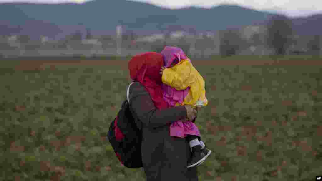 Une femme tient son bébé dans ses bras alors que s&rsquo;abat une pluie diluvienne près du poste-frontière grec d&rsquo;Idomeni dans le nord de la Grèce, le 4 mars 2016.
