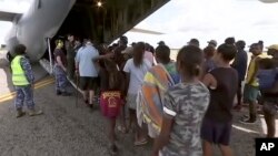 In this image made from video March 21, 2019, storm evacuees board an Australian Defense Force C-130 plane preparing in Borroloola, Australia, before the arrive of two powerful cyclones to Australia's sparsely populated north.