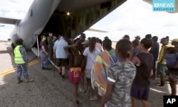 In this image made from video March 21, 2019, storm evacuees board an Australian Defense Force C-130 plane preparing in Borroloola, Australia, before the arrive of two powerful cyclones on Australia's sparsely populated north where about 2,000 people were evacuated.
