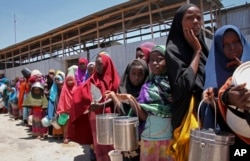 FILE - In this photo taken Feb. 25, 2017, displaced Somali girls who fled the drought in southern Somalia stand in a queue to receive food handouts at a feeding center in a camp in Mogadishu, Somalia.