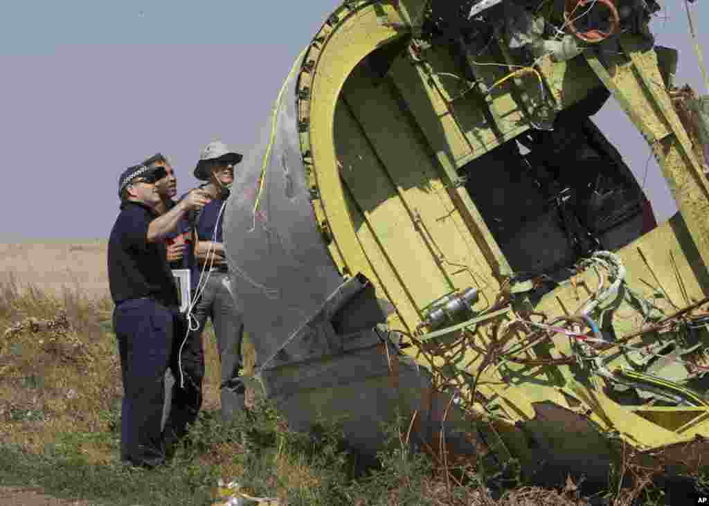 Australian and Dutch experts examine a piece of the Malaysia MH17 plane, near the village of Hrabove, Donetsk region, eastern Ukraine, Aug.1, 2014. 