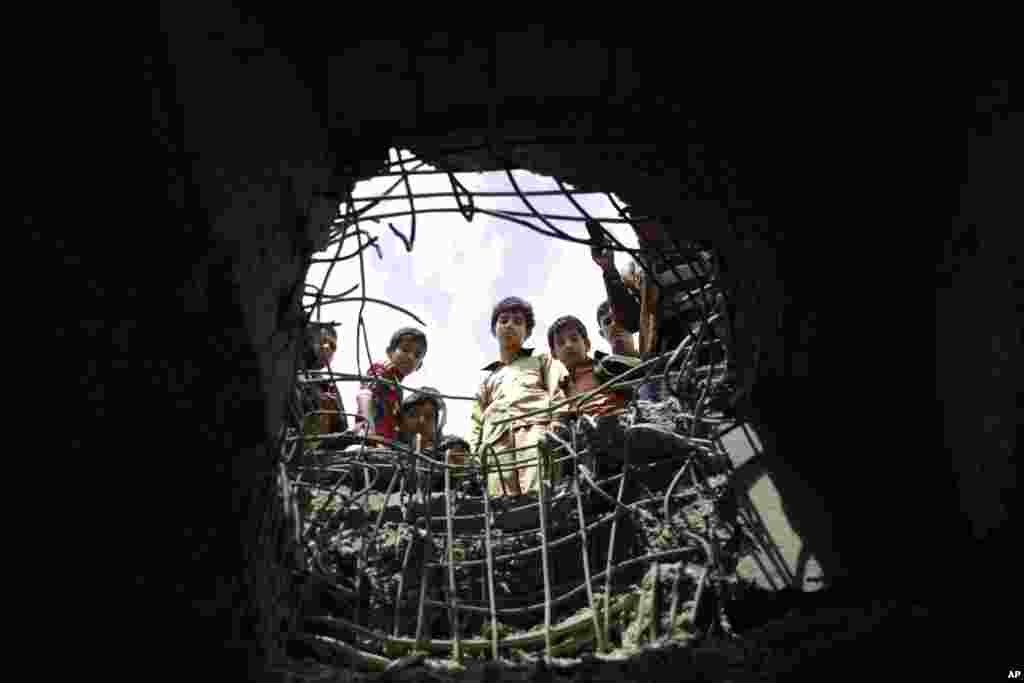 Boys look through a hole caused by a Saudi-led airstrike on a bridge in Sana&#39;a, Yemen.