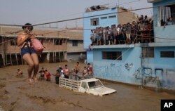 A woman is pulled to safety in a zipline harness in Lima, Peru, March 17, 2017.