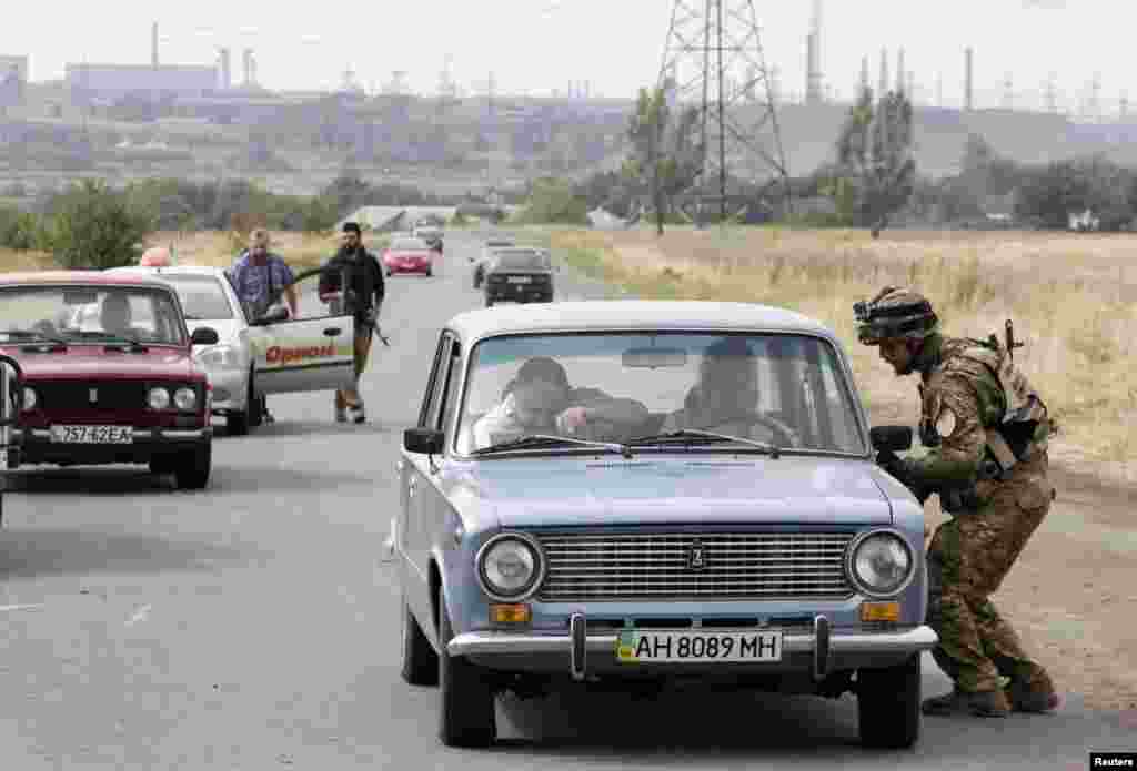 Soldiers from the Ukrainian self-defence battalion "Azov" check vehicles at a checkpoint in the southern coastal town of Mariupol, Sept. 8, 2014.