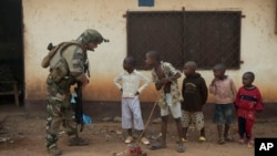 A French soldier talks to curious children as he mans a roadblock in the Miskine neighborhood of Bangui, Central African Republic, Jan. 6, 2014. 