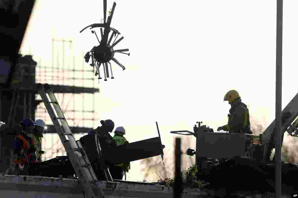 Scottish Fire and Rescue services examine a section of a police helicopter after crashing into the Clutha Bar in Glasgow, Scotland. Emergency workers sifted through wreckage for survivors from the crowded pub that killed at least eight people and injured more than two dozen.