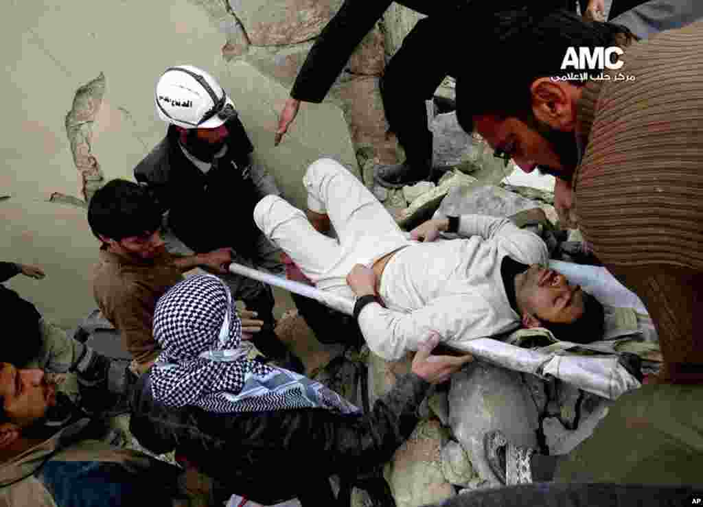 This citizen journalism image provided by Aleppo Media Center shows Syrian residents and rescue workers carrying an injured man after an airstrike in Aleppo, Jan. 23, 2014.