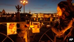 A woman reacts standing at pictures of the plane crash victims are attached to the fence at Dvortsovaya (Palace) Square in St.Petersburg, Russia, Nov. 3, 2015. 