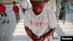 A Rohingya Muslim with the word "Rohingya" written on his T-shirt prays with others at a makeshift mosque at a camp for those displaced by violence, near Sittwe April 28, 2013.