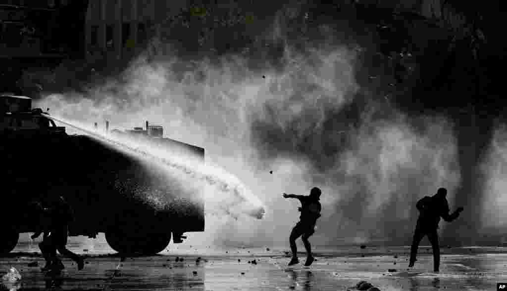 Demonstrators are sprayed with a police water cannon during an anti-government protest in Santiago, Chile, Nov. 5, 2019.